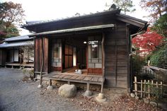 a small wooden building with two windows and a door on the outside, surrounded by trees