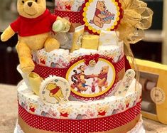 a winnie the pooh themed diaper cake with teddy bear on top and other items