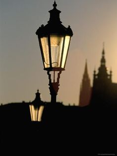 an old fashioned street light in front of a castle