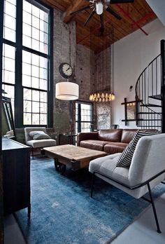 a living room filled with furniture and a spiral staircase in front of a large window