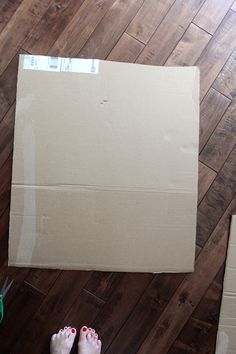 a cardboard box sitting on top of a hard wood floor next to scissors and tape