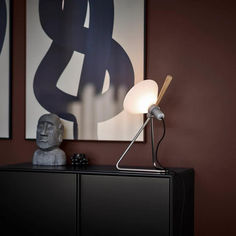 a lamp sitting on top of a black cabinet next to a painting and a statue