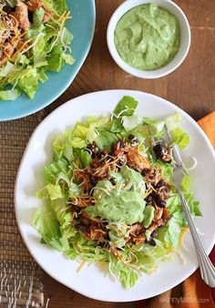 two plates filled with lettuce, chicken and guacamole