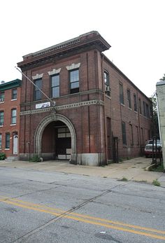 an old brick building on the corner of a street with no cars parked in front