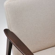 a close up view of a wooden armrest on a beige chair with a white background