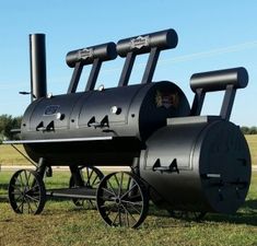 a large black bbq sitting on top of a grass covered field