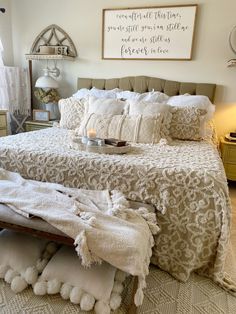 a bedroom with a large bed covered in white blankets and throw pillows on the floor