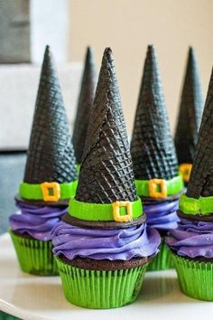 cupcakes decorated like witches with green and purple frosting on top, sitting on a plate