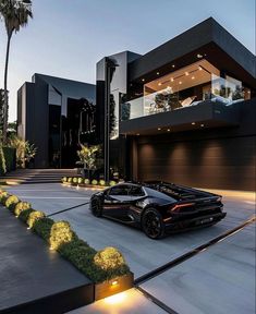 a black sports car is parked in front of a modern house at night with its lights on