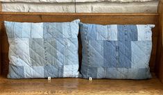 two blue pillows sitting on top of a wooden bench