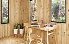 a room with wood paneling and two windows that look out onto the woods,