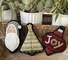 three christmas ornaments sitting on top of a table next to plants and potted plants