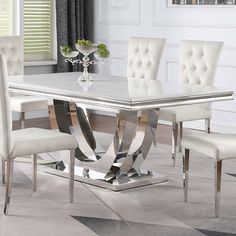 a dining table with white chairs and a silver centerpiece on top of the table