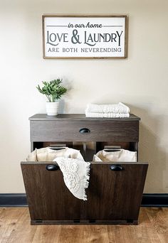 a wooden cabinet with two drawers in front of a sign that says love and laundry are both neverending