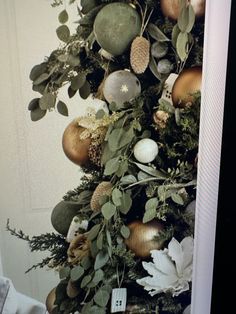 a christmas tree with ornaments hanging from it's sides and greenery on the top