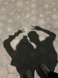 the shadow of a person holding a cell phone up to their head on a tiled floor