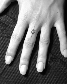 a person's hand with a small star tattoo on it