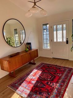 a living room with a rug, mirror and plant on the floor in front of it