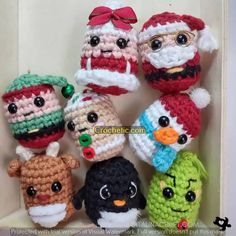 crocheted christmas ornaments are arranged in a row on a shelf with the faces of santa claus, snowman, penguin and other characters