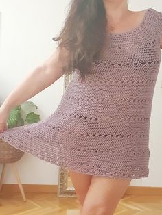 a woman in a short crochet dress posing for the camera