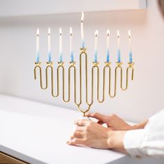 a person lighting candles on a menorah