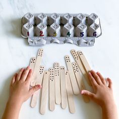 two hands reaching for dominoes in front of an egg carton with numbers on them