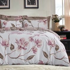 a bed with pink flowers on it and two pictures hanging above the headboard,