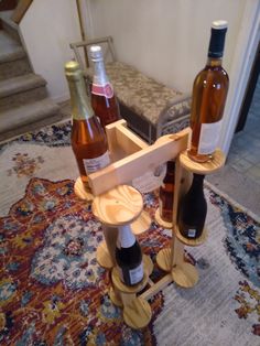 three bottles of wine are sitting in a holder on the floor next to a stair case