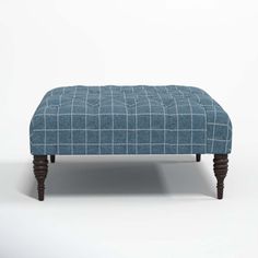 a blue foot stool with wooden legs and a checkered pattern on the top, in front of a white background