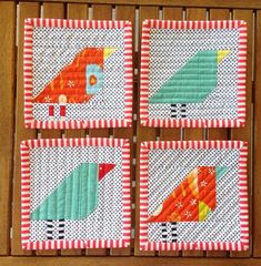 four coasters with colorful birds on them