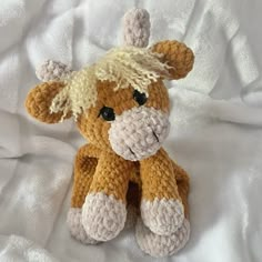 a brown and white stuffed animal sitting on top of a bed