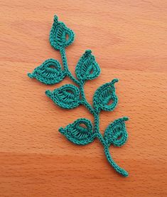 a crocheted leaf on a wooden surface