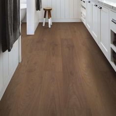 a kitchen with white cabinets and wood flooring on the walls, along with a wooden stool