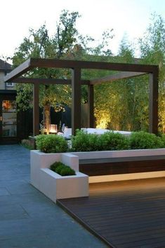 a wooden bench sitting next to a lush green park filled with trees and bushes at night