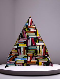 a white table topped with a multicolored triangle shaped book shelf filled with books