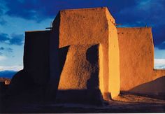 an adobe building in the desert under a cloudy sky