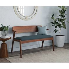 a wooden bench sitting next to a potted plant on top of a rug covered floor