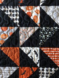 an orange and black patchwork quilt with pumpkins, bats and polka dots on it