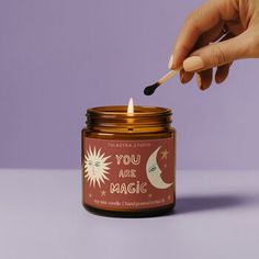 someone lighting a candle in a jar with the words you are magic written on it