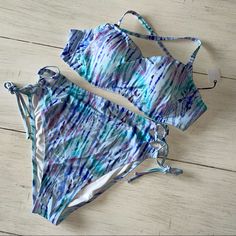 Tie Dye Bikini In Shades Of Blue And Purple. Features A Halter Neck And High Waisted Bottoms. Top Has Underwire And Is Size 36d. According To Attached Tag, Top Provides Light Lift. Bottoms Feature Lace Up Side Ties And Are Size Large. New With Tag Attached. Attached Tag Is Not The Price Tag, But Is Other Informational Tag. All Items From A Smoke Free Environment. Blue Underwire Lined Swimwear, Bra-friendly Purple Swimwear With Underwire, Purple Underwire Swimwear, Bra Friendly, Purple Underwire Swimwear, Bra-friendly, Purple Bra-friendly Underwire Swimwear, Purple Underwire Swimwear For Beach Season, Purple Underwire Beachwear Swimwear, Blue Tankini With Padded Cups For Summer, Red Bralette