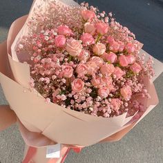 a person holding a bouquet of pink roses