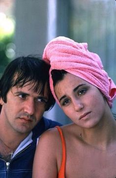 a man and woman with pink towels on their heads posing for a photo in front of a building