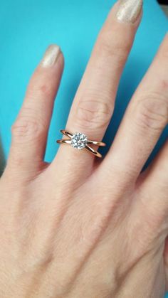 a woman's hand with a diamond ring on her left hand, against a blue background