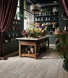 a room filled with lots of plants and vases on top of a wooden table