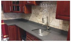 a kitchen with wooden cabinets and granite counter tops, wine glasses on the sink faucet