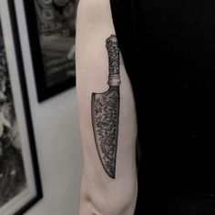 a man with a knife tattoo on his arm, holding a knife in the other hand