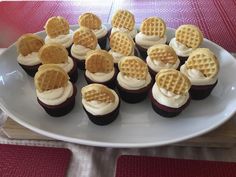 a white plate topped with chocolate cupcakes covered in waffles and frosting