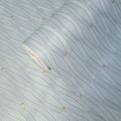 an up close view of a bed with white sheets and gold dots on the covers