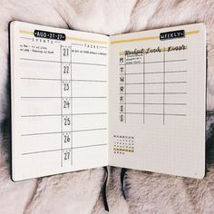 an open planner book sitting on top of a white fur covered bed next to a pen