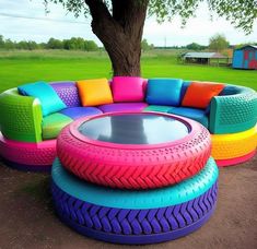 an unusual couch made out of old tires and other colorful furniture in a park setting